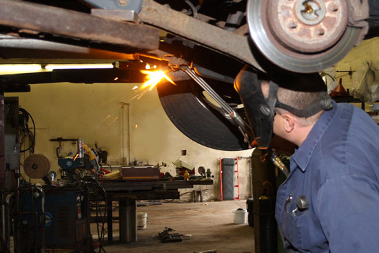 Mechanic welding an exhaust system